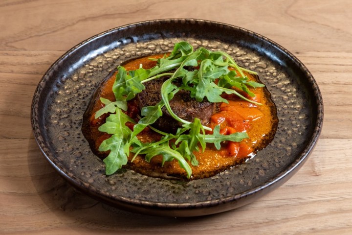 a bowl of food sitting on top of a wooden table